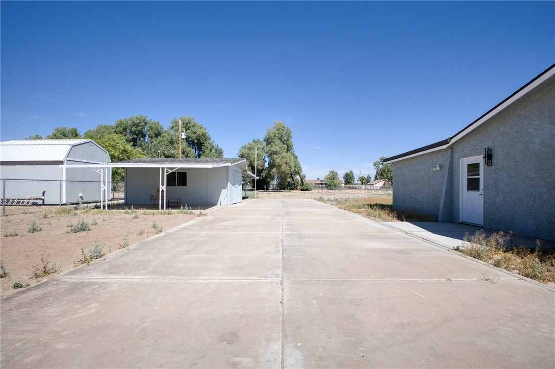2053 Regents Road Mohave Valley, AZ 86440 - Photo 38 of 65 Concrete driveway leading to the property, which features a light blue stucco exterior and a white door with a black light fixture