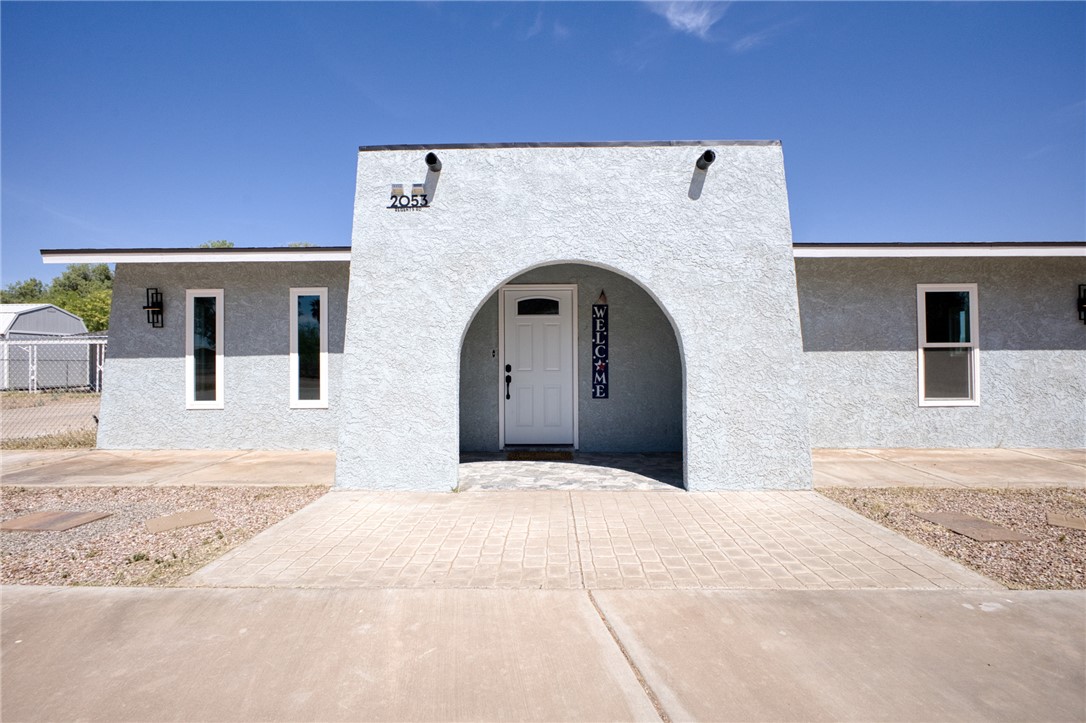 2053 Regents Road Mohave Valley, AZ 86440 - Photo 3 of 65 The property features a stucco exterior, an arched entryway, and a white front door