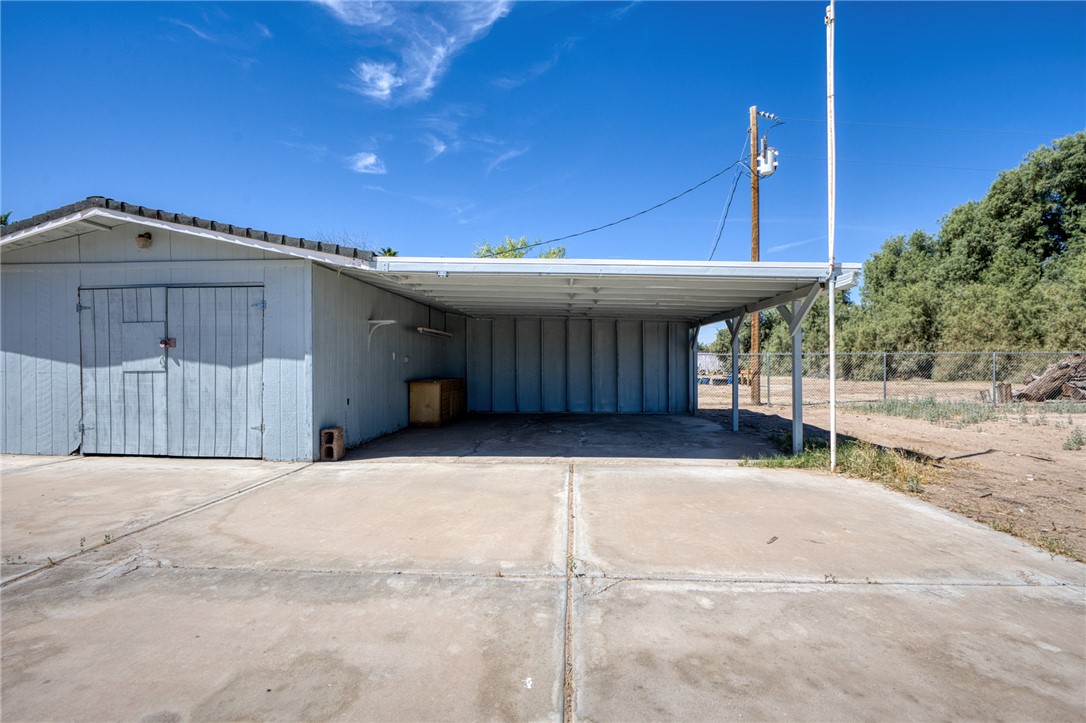 2053 Regents Road Mohave Valley, AZ 86440 - Photo 40 of 65 The property features a dedicated storage building with a large wooden door, and an attached carport providing covered parking