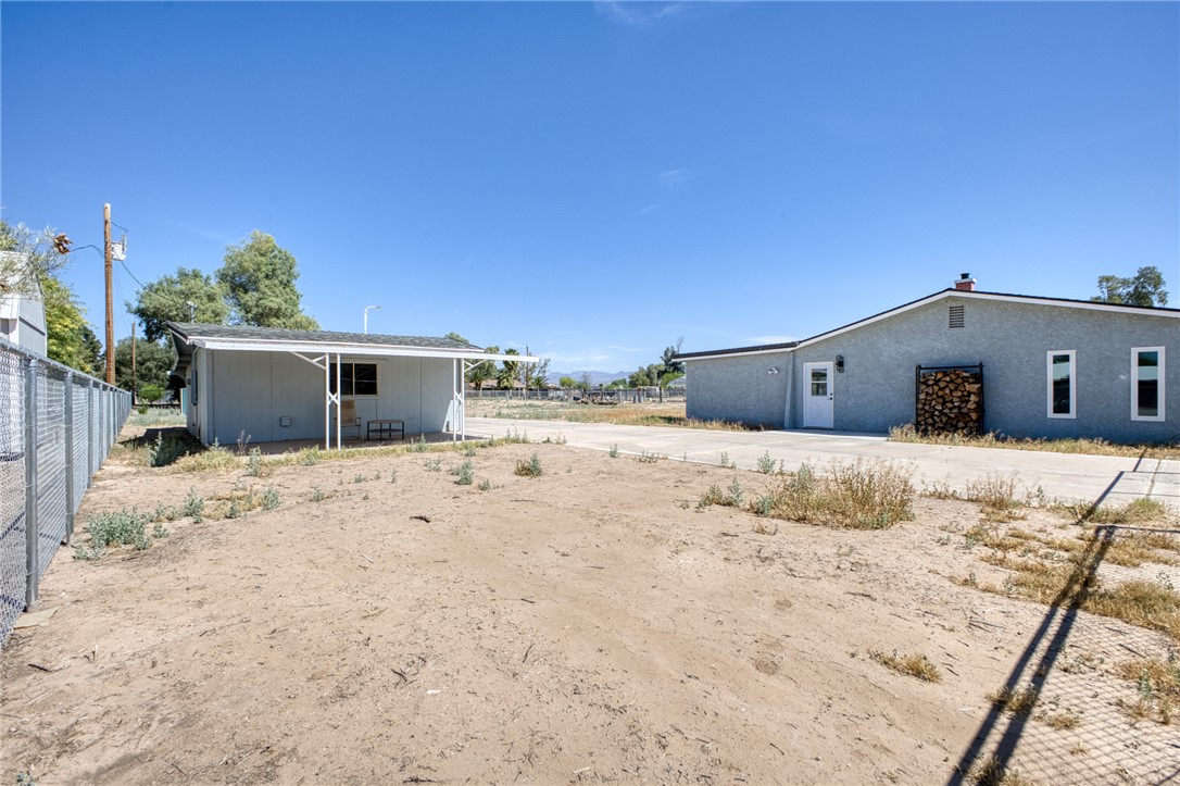 2053 Regents Road Mohave Valley, AZ 86440 - Photo 49 of 65 The property features a spacious yard with a chain-link fence, a separate outbuilding with a covered porch, and a main structure with multiple windows and a white entry door