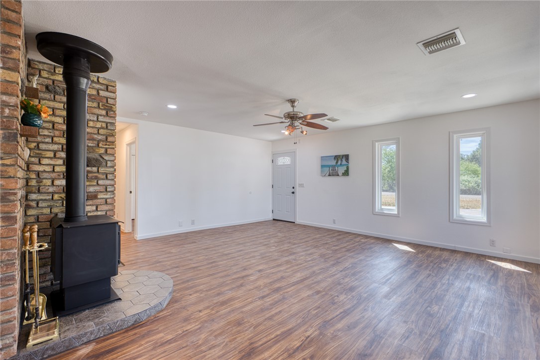 2053 Regents Road Mohave Valley, AZ 86440 - Photo 6 of 65 Spacious living area featuring an exposed brick fireplace with a wood-burning stove, wood-look flooring, and recessed lighting