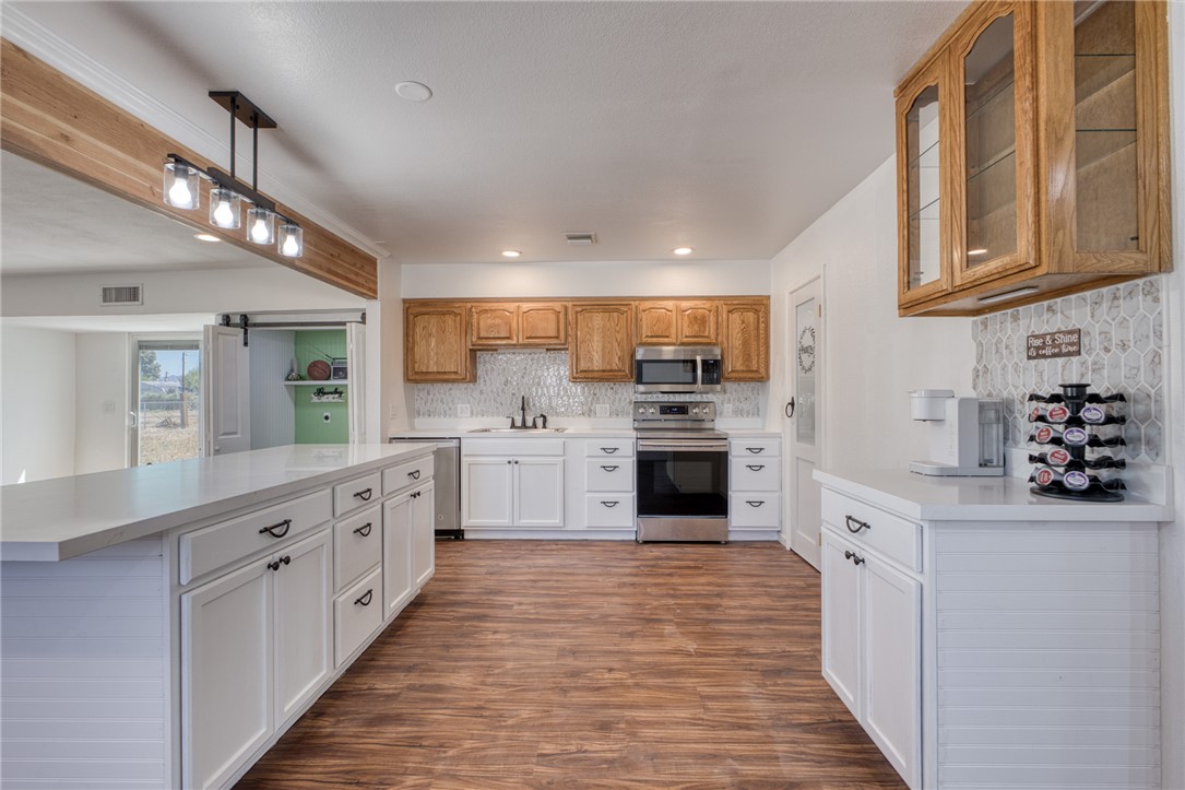 2053 Regents Road Mohave Valley, AZ 86440 - Photo 8 of 65 The kitchen features wood-look flooring, white cabinetry with dark hardware, a spacious island, and stainless steel appliances