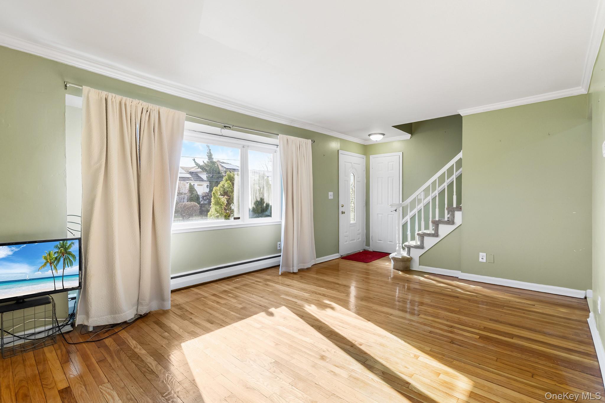 119 Osborne Road West Hempstead, NY 11552 - Photo 6 of 34 a view of an empty room with window and wooden floor