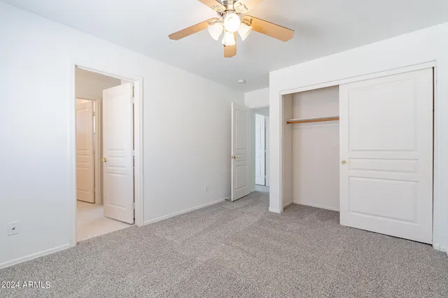 an empty room with closet and a chandelier fan