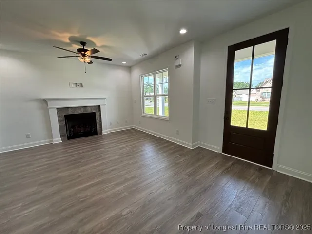 a view of an empty room with wooden floor fireplace and a window