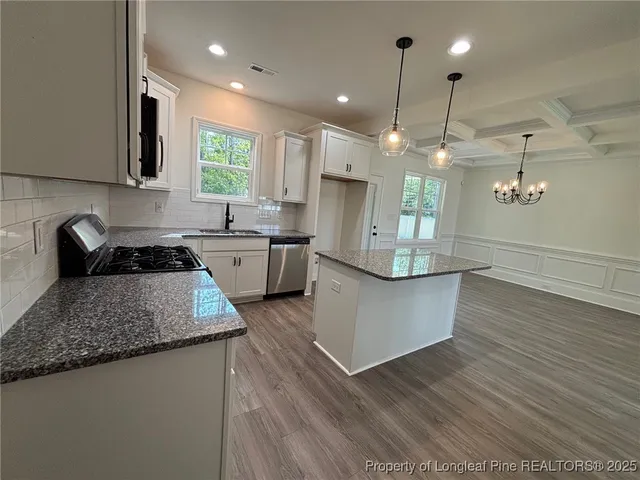 a kitchen with granite countertop a sink cabinets and wooden floor
