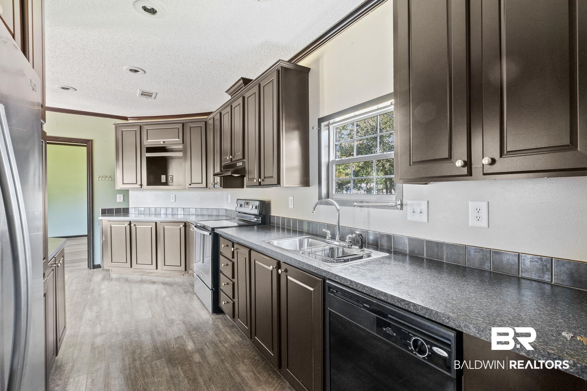 6870 Cecilia Court Theodore, AL 36582 - Photo 24 of 83 Kitchen with sink, dark brown cabinets, stainless steel appliances, crown molding, and dark hardwood / wood-style flooring