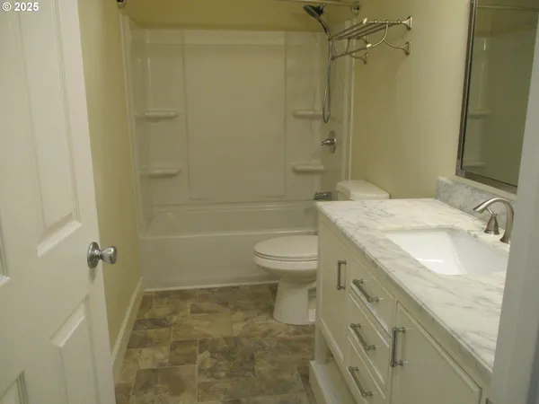 a bathroom with a granite countertop sink and a toilet