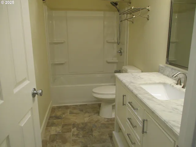 a bathroom with a granite countertop sink and a toilet