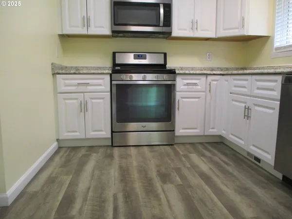 a kitchen with granite countertop white cabinets and stainless steel appliances