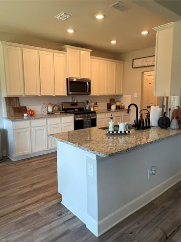 a kitchen with granite countertop a sink a counter top space cabinets and stainless steel appliances