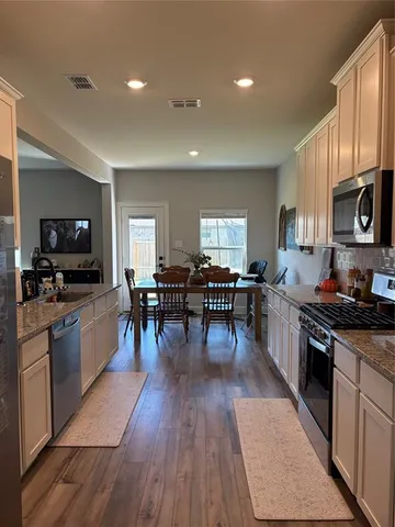 a large kitchen with cabinets wooden floor and stainless steel appliances