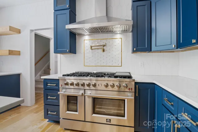 a stove top oven sitting inside of a kitchen with stainless steel appliances wooden cabinets and a stove