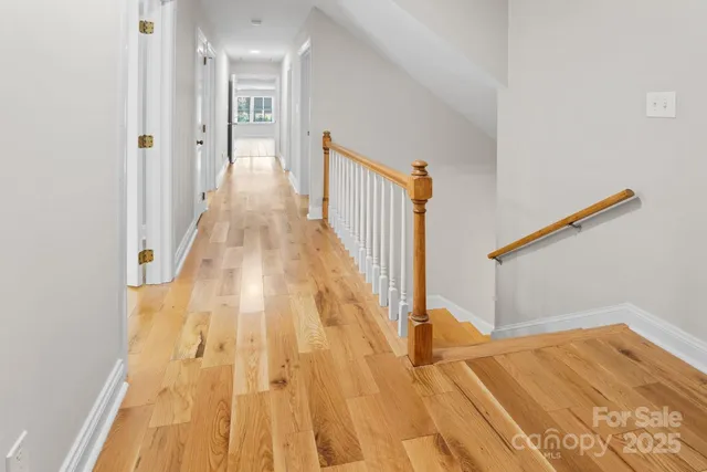 a view of a hallway with wooden floor and staircase