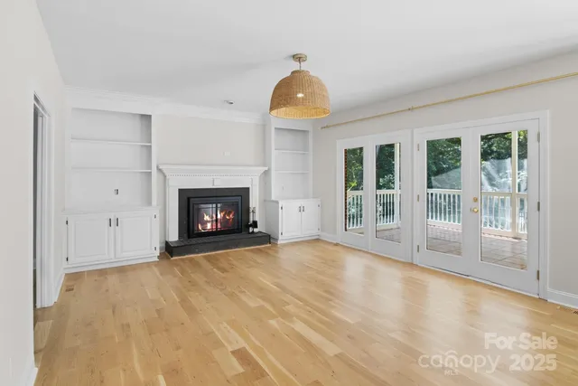 a view of an empty room with glass door and wooden floor