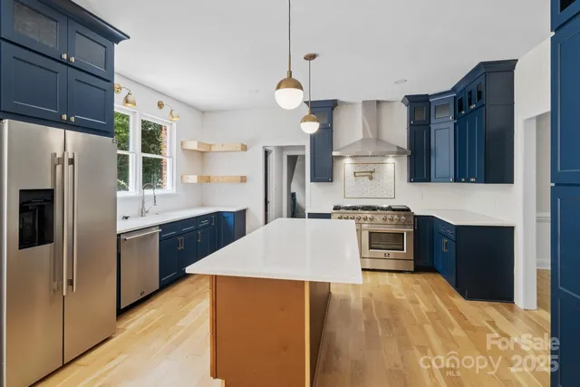 a large kitchen with stainless steel appliances kitchen island granite countertop a stove refrigerator and cabinets