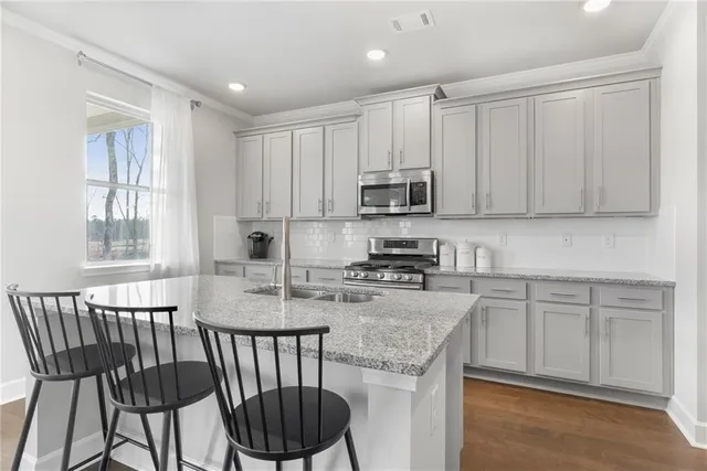 a kitchen with stainless steel appliances granite countertop a stove a sink a microwave a dining table and chairs
