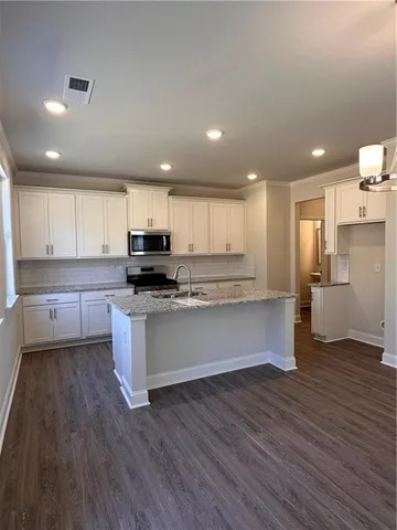 a large kitchen with cabinets wooden floor and a stainless steel appliances