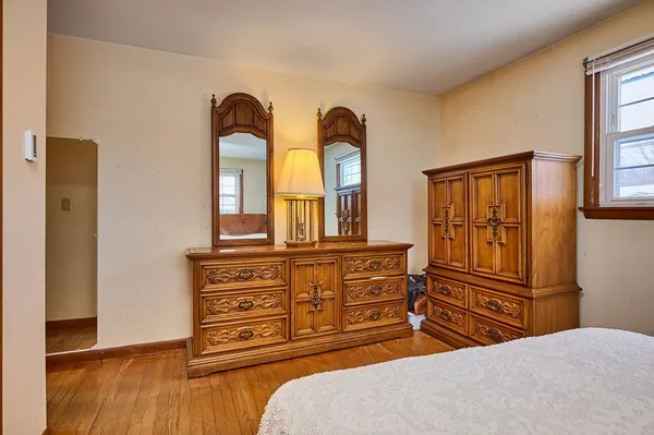 a bedroom with a dresser and wooden floor