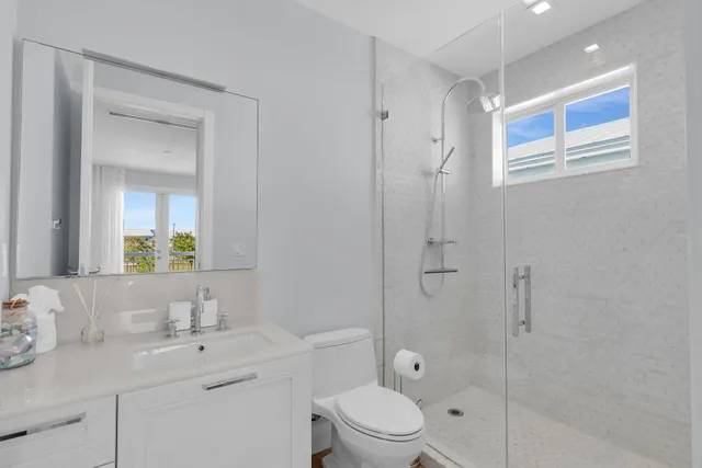 a bathroom with a toilet a sink a mirror a shower and vanity