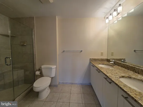 a bathroom with a granite countertop sink a toilet and shower