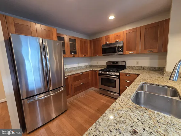 a kitchen with granite countertop stainless steel appliances a refrigerator a sink a stove a microwave and cabinets