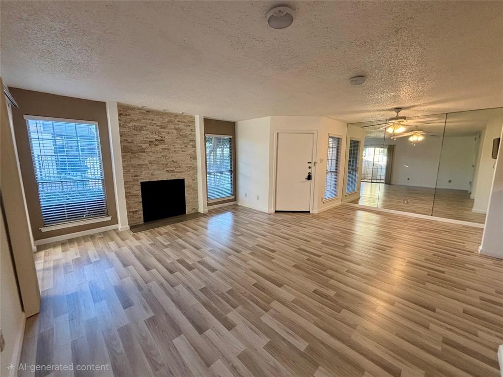 12480 Abrams Road, Unit 2805 Dallas, TX 75243 - Photo 3 of 18 Unfurnished living room with a textured ceiling, light wood finished floors, a ceiling fan, and a fireplace