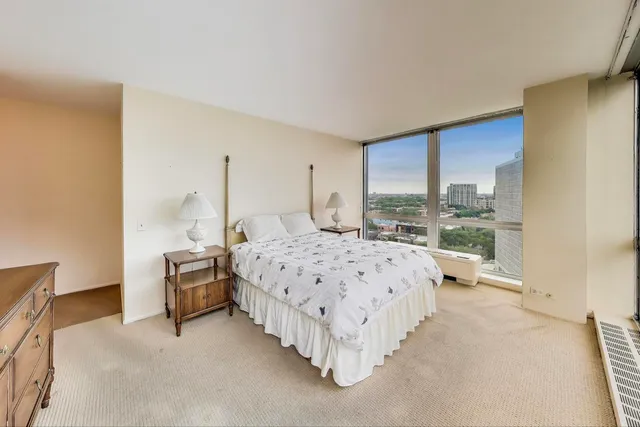 a large bedroom with a bed and a dresser next to a window