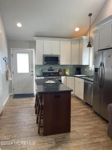 a kitchen with stainless steel appliances granite countertop a stove a sink dishwasher a refrigerator and a microwave