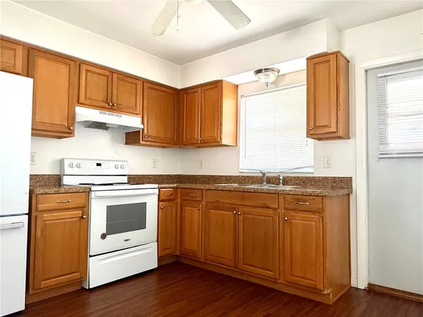 a kitchen with stainless steel appliances granite countertop a sink and cabinets with wooden floors