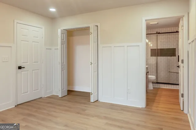 a view of a hallway with wooden floor and a bathroom