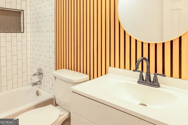 a bathroom with a granite countertop sink a toilet and bathtub