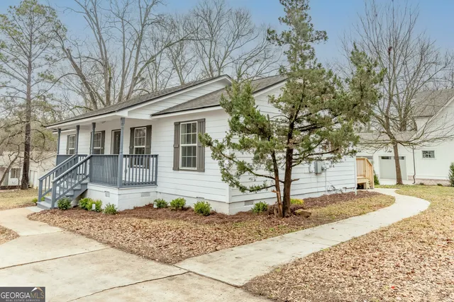 a front view of a house with a yard and large tree
