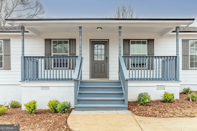 a view of a house with a small yard and wooden floor and seating space