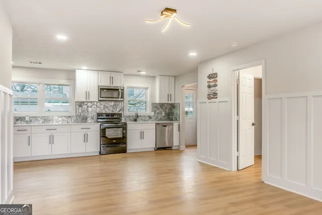 a kitchen with stainless steel appliances white cabinets and wooden floor