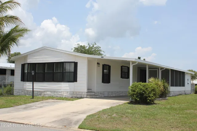 a front view of a house with a yard and potted plants