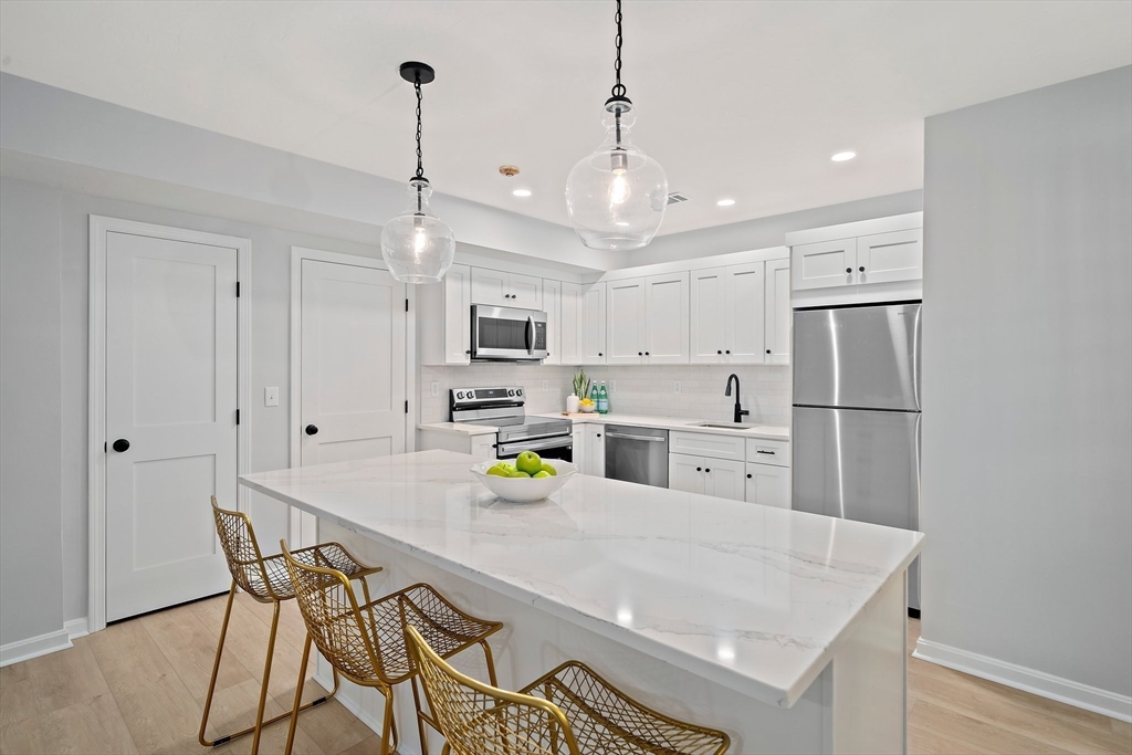 192 Allerton Commons Lane, Unit 192 Braintree, MA 02184 - Photo 9 of 17 a kitchen with stainless steel appliances a refrigerator a sink dishwasher a stove and white cabinets with wooden floor