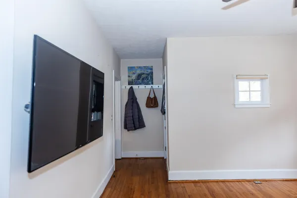 a view of a hallway with wooden floor and a livingroom with entryway