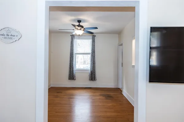 a view of an empty room with window and wooden floor
