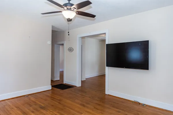 an empty room with wooden floor fan and windows