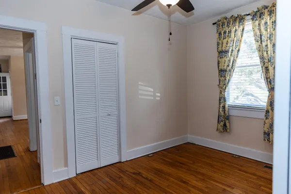 an empty room with wooden floor cabinet and windows