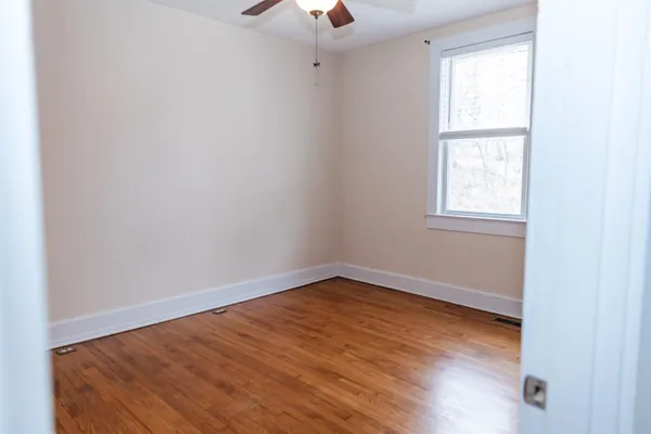 an empty room with a window and wooden floor