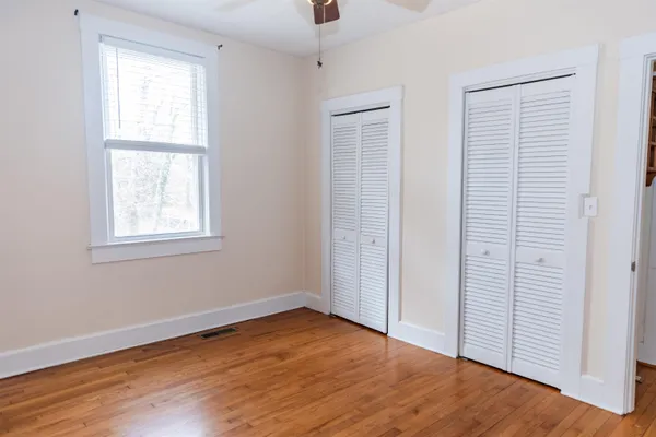 a view of empty room with wooden floor and fan