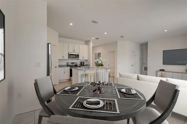 a view of a dining room with furniture a kitchen and chandelier