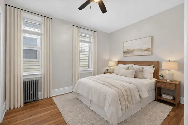 an empty room with wooden floor fan and windows