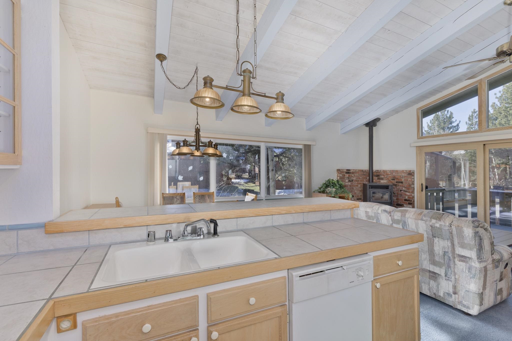 3251 Chateau Road, Unit 40 Mammoth Lakes, CA 93546 - Photo 31 of 31 Kitchen featuring tile counters, a wood stove, lofted ceiling with beams, white dishwasher, and open floor plan