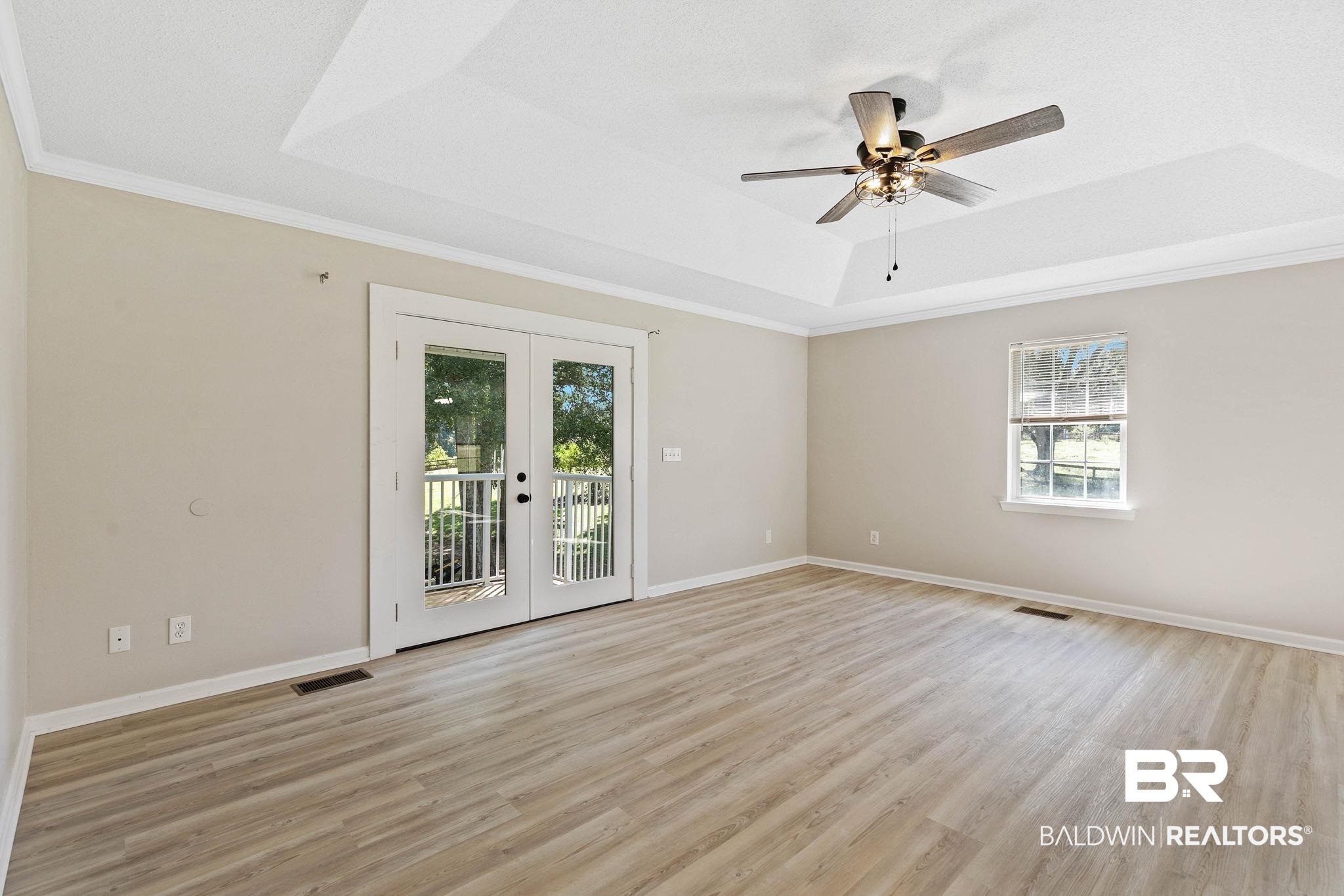35650 Spring Road North Stapleton, AL 36578 - Photo 31 of 70 Empty room with a raised ceiling, french doors, ornamental molding, light wood finished floors, and ceiling fan
