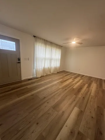 a view of an empty room with window and wooden floor