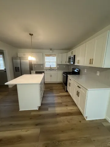 a large white kitchen with kitchen island a sink a stove and cabinets