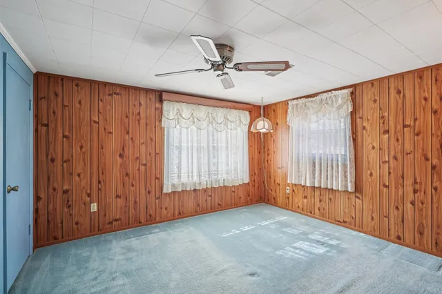 an empty room with windows & a ceiling fan